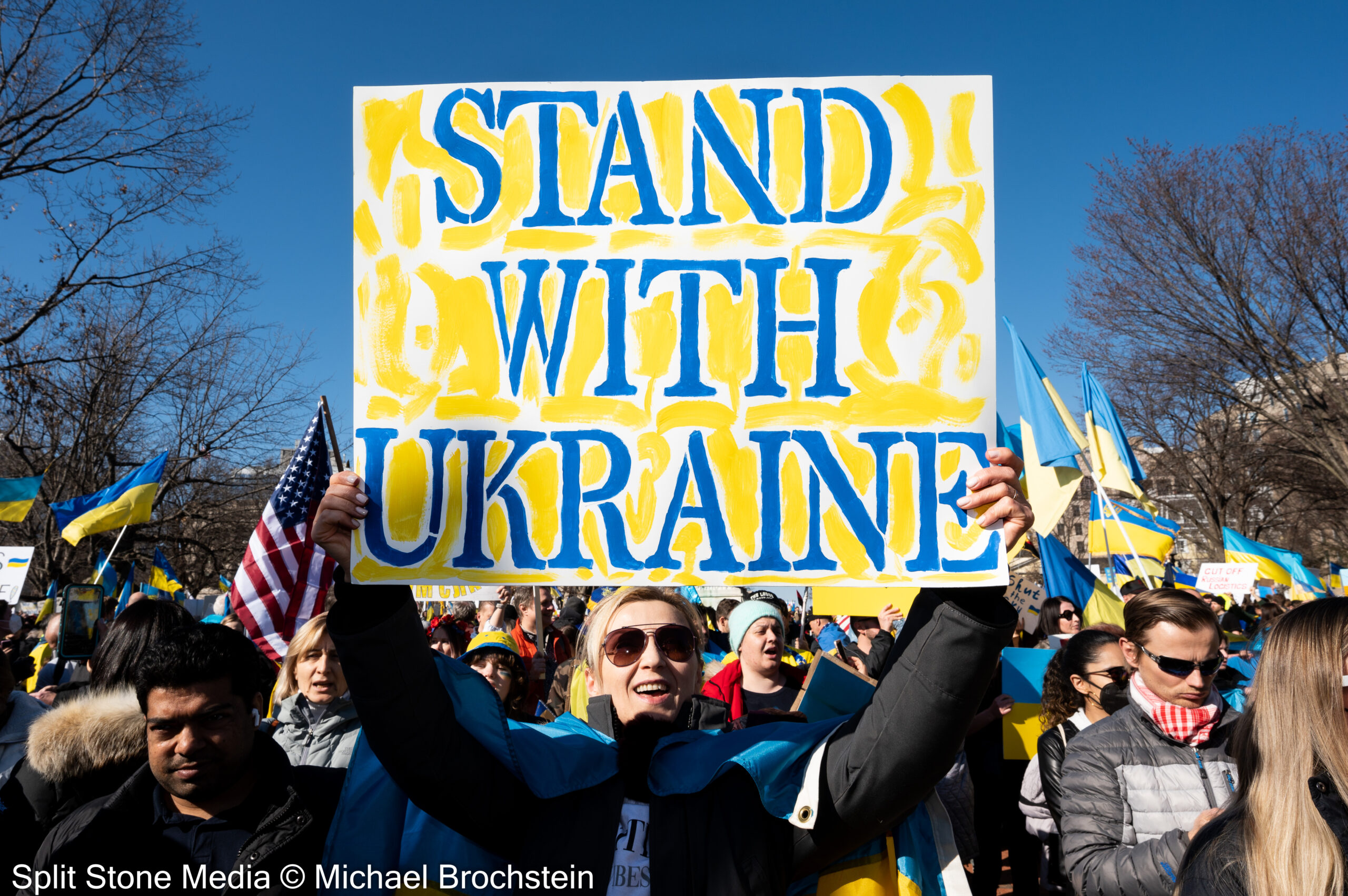 Protesters holding a sing that reads stand with ukriane